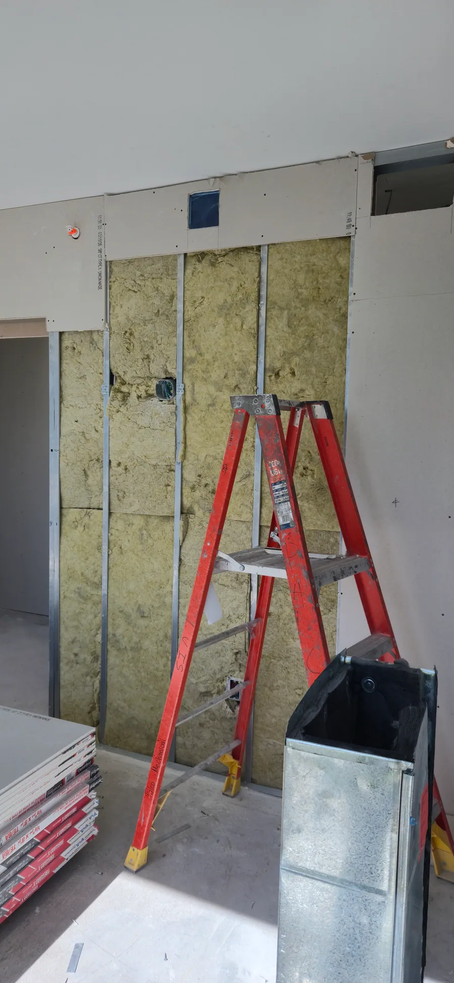 Batt insulation fitted between wall studs before drywall board installation