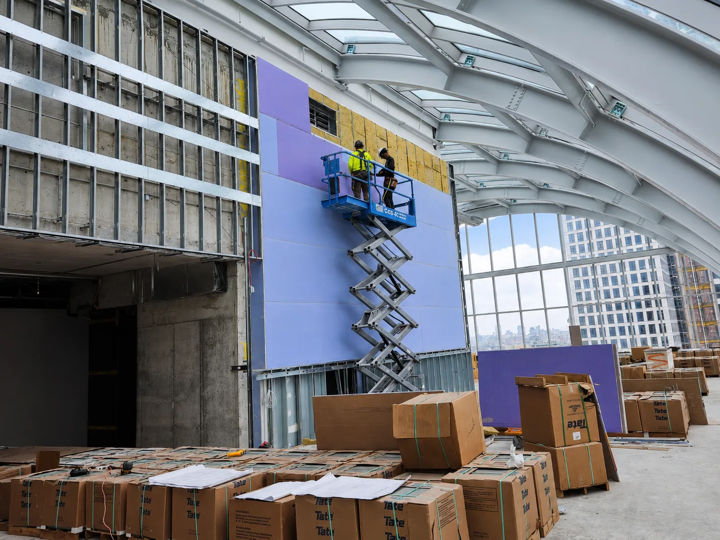 Commercial drywall crew installing wall board using approved access equipment available at the project
